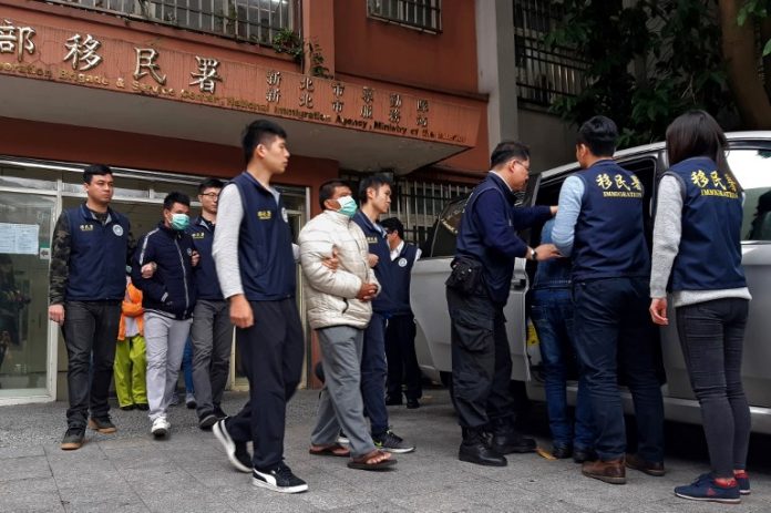 Taiwan immigration officers escort three detained men (with masks), believed to be some of the 152 Vietnamese who went missing after arriving on the island, into a vehicle outside the immigration offices in New Taipei City on December 28, 2018. - Authorities said on December 26 that a search was underway for 152 Vietnamese who arrived in Taiwan on tourist visas, as local media reported they may have come to the island to work illegally. (Photo by HSU Tsun-hsu / AFP)
