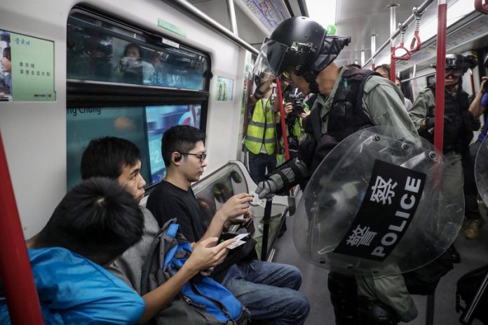 Policier de la brigade anti-émeute hongkongaise effectuant un contrôle d'identité dans le métro (photo CNA)